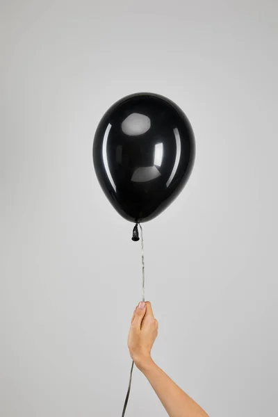 Vista cortada de mulher segurando balão preto isolado em cinza, conceito de sexta-feira preta — Fotografia de Stock