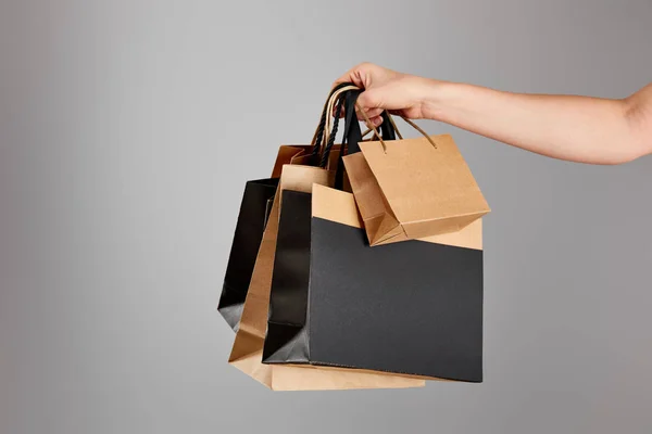Vista cortada de mulher segurando saco de compras de papel isolado no conceito cinza, preto sexta-feira — Fotografia de Stock