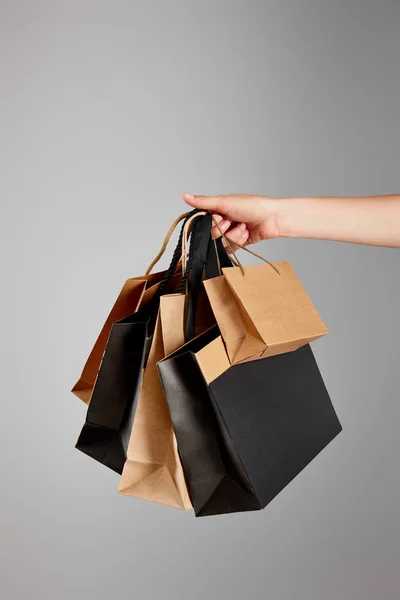 Vista parcial de la mujer sosteniendo bolsa de compras de papel aislado en gris, concepto de viernes negro - foto de stock