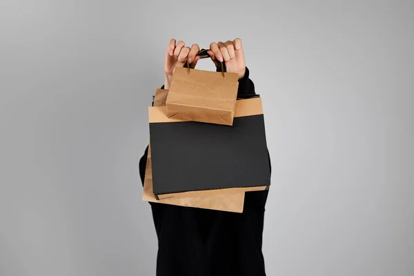 Frau mit undurchsichtigem Gesicht hält Papiereinkaufstüten isoliert auf grauem, schwarzem Freitag-Konzept — Stockfoto