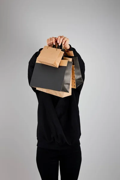 Mujer con cara oscura sosteniendo bolsas de compras de papel aisladas en gris, concepto de viernes negro - foto de stock