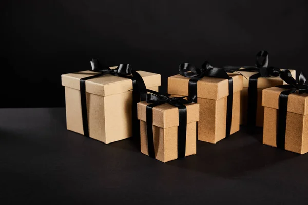 Cardboard gift boxes with black ribbons isolated on black, black Friday concept — Stock Photo