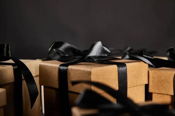 Vista de cerca de cajas de regalo de cartón con cintas negras aisladas en negro, concepto de viernes negro - foto de stock