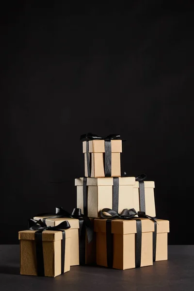 Стопка картонних подарункових коробок з чорними стрічками ізольовані на чорній, чорній концепції п'ятниці — стокове фото