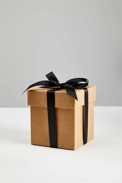 Cardboard gift box with black ribbon isolated on grey, black Friday concept — Stock Photo