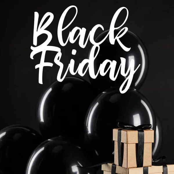 Racimo de globos negros cerca de pila de cajas de regalo aisladas en negro con ilustración de viernes negro - foto de stock