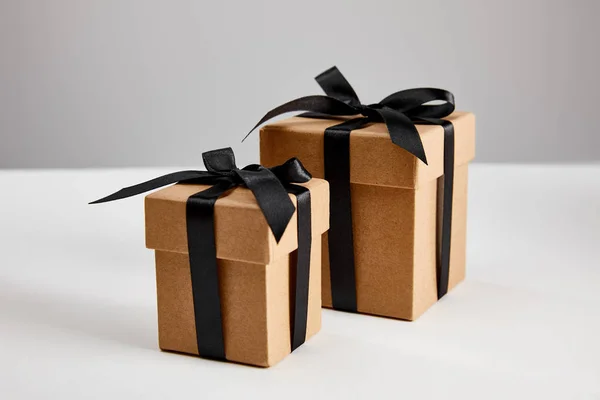 Cardboard gift boxes with black ribbons isolated on grey, black Friday concept — Stock Photo