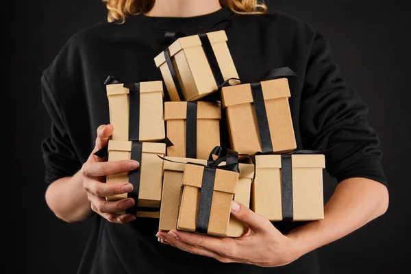 Vista cortada de mulher segurando caixas de presente de papelão com fitas isoladas em preto, conceito de sexta-feira preta — Fotografia de Stock