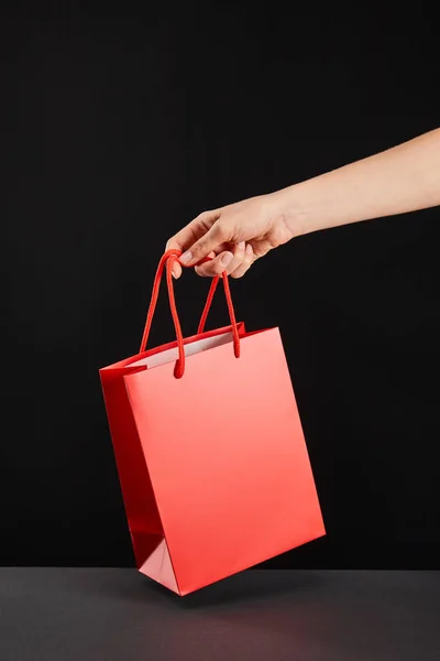 Partial view of woman holding red shopping bags isolated on black, black Friday concept — Stock Photo