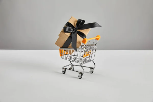 Geschenkkarton mit schwarzem Band in kleinem Warenkorb isoliert auf grau, Black Friday Konzept — Stockfoto