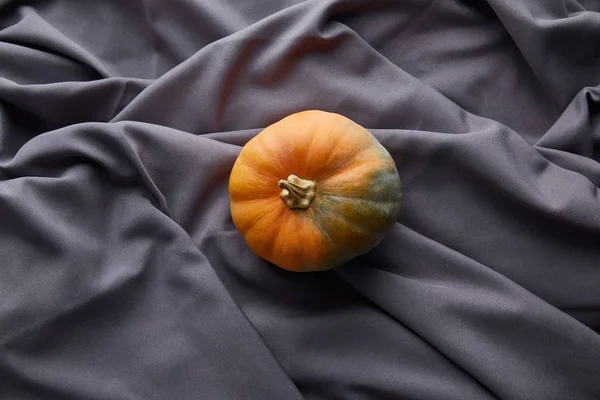 Ripe whole colorful pumpkin on grey cloth — Stock Photo