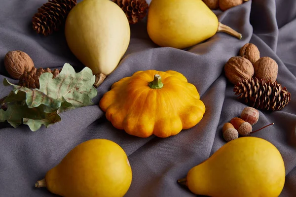 Calabazas coloridas enteras maduras y decoración otoñal sobre tela gris - foto de stock