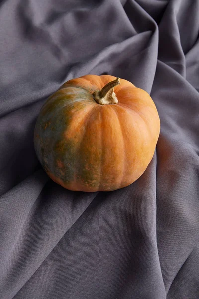 Calabaza colorida entera madura en tela gris - foto de stock