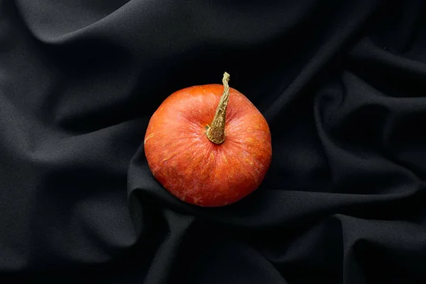 Top view of ripe whole colorful pumpkin on black cloth — Stock Photo