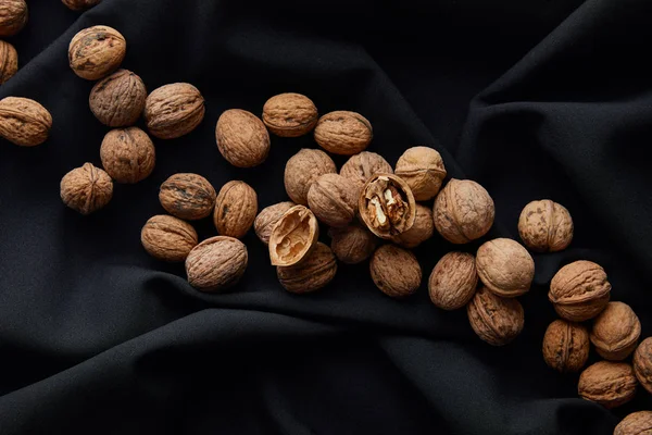 Vue de dessus des noix brunes sur tissu noir — Photo de stock