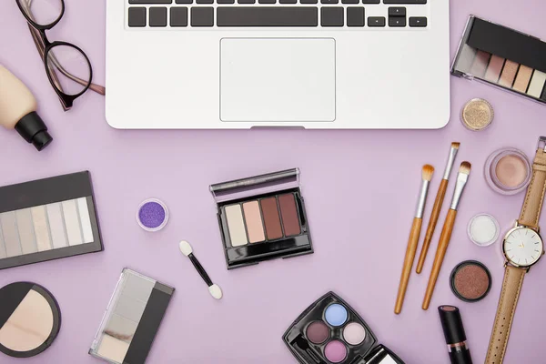 Top view of laptop near decorative cosmetics isolated on violet — Stock Photo