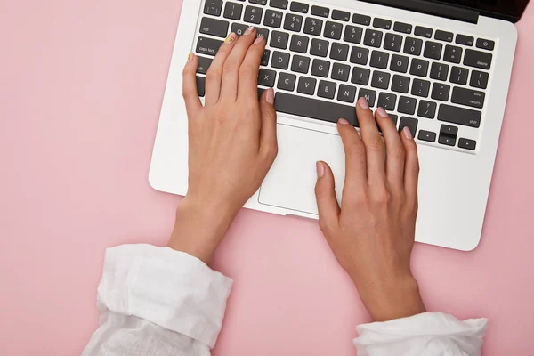 Vista dall'alto della donna digitando sul computer portatile isolato su rosa — Foto stock