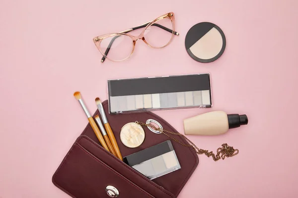 Top view of glasses near bag with decorative cosmetics isolated on pink — Stock Photo