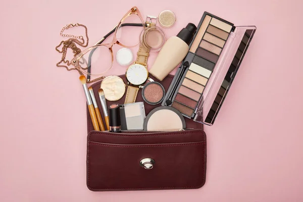 Top view of brown bag near decorative cosmetics and watch isolated on pink — Stock Photo