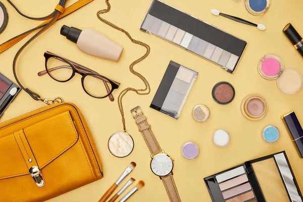 Top view of bag near glasses and decorative cosmetics isolated on yellow — Stock Photo