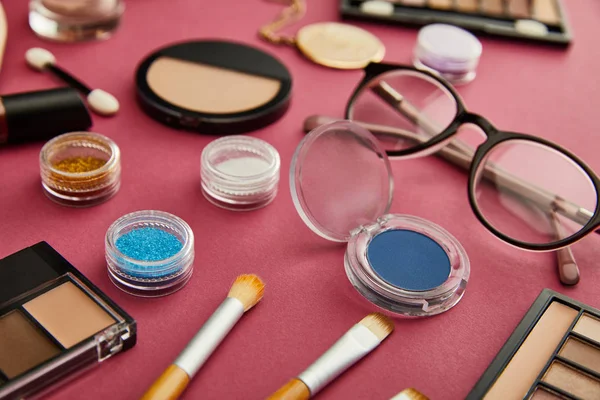 Selective focus of cosmetic brushes near glasses on crimson — Stock Photo