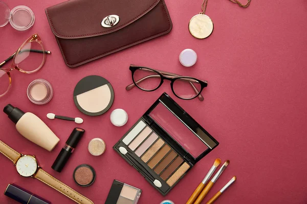 Top view of brown bag near glasses and lipsticks on crimson — Stock Photo
