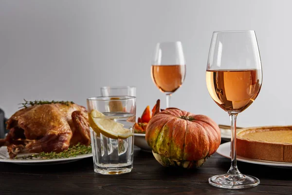 Gebackener Kürbis, gegrillter Truthahn, Kürbiskuchen, Gläser mit Rosenwein und Zitronenwasser auf Holztisch isoliert auf grau — Stockfoto