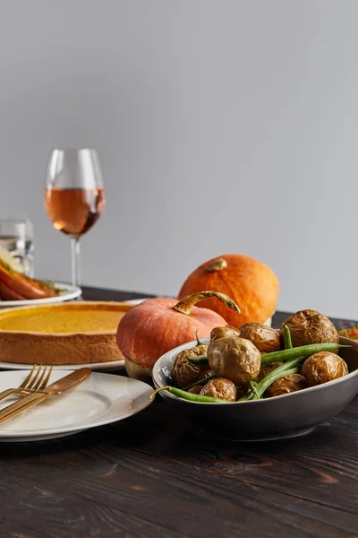 Calabazas y patatas horneadas, tarta de calabaza y copa con vino rosa sobre mesa de madera aislada en gris - foto de stock