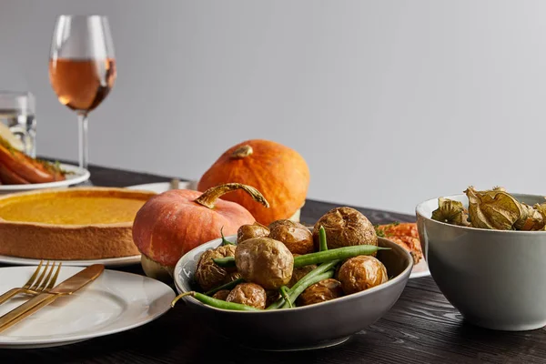 Citrouilles et pommes de terre cuites au four, tarte à la citrouille et verre avec vin rose sur table en bois isolé sur gris — Photo de stock