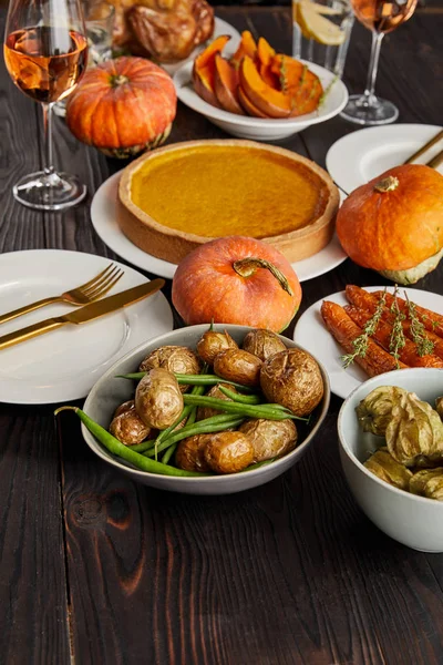 Pastel de calabaza, patatas al horno, calabazas y zanahorias en la mesa de madera - foto de stock