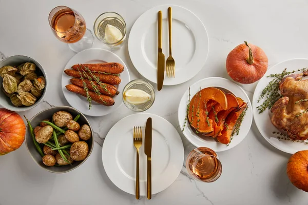 Vista superior de la cena festiva de acción de gracias con verduras horneadas y pavo a la parrilla servido en la mesa de mármol blanco - foto de stock