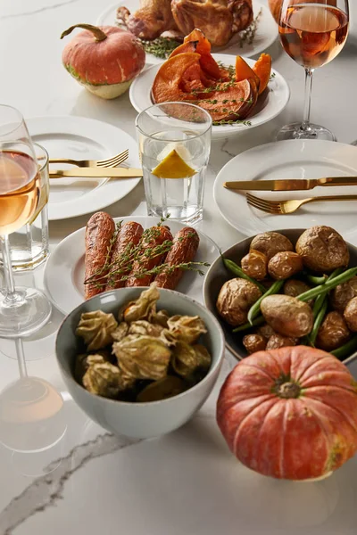Servi le dîner de Thanksgiving avec dinde grillée, légumes cuits au four et citrouilles entières sur table en marbre blanc — Photo de stock
