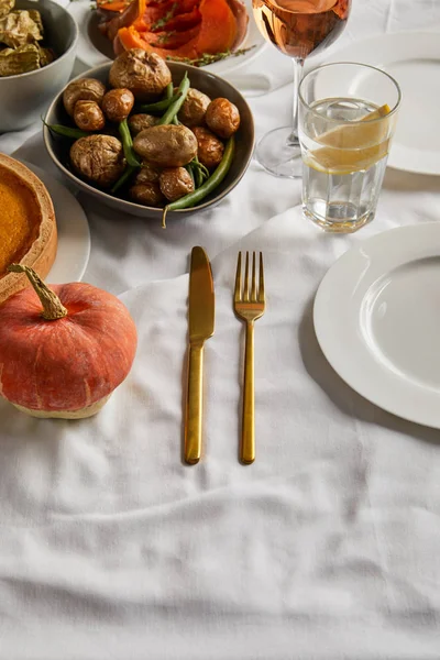 Печеная картошка, стаканы с белой розой и лимонной водой и столовые приборы на белой скатерти — стоковое фото