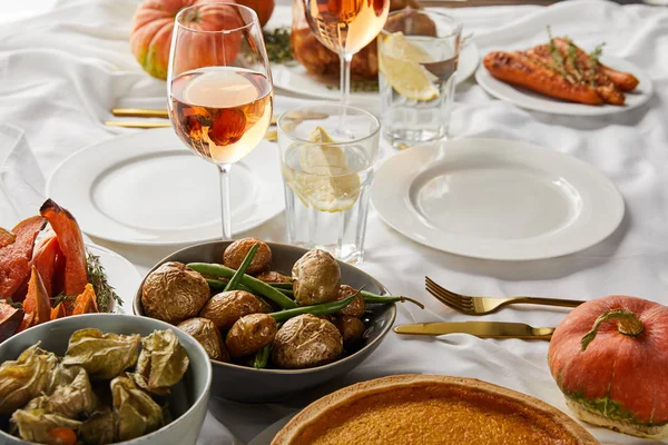 Pomme de terre cuite au four et physalis près des verres avec du vin de rose et de l'eau de citron sur la nappe blanche — Photo de stock