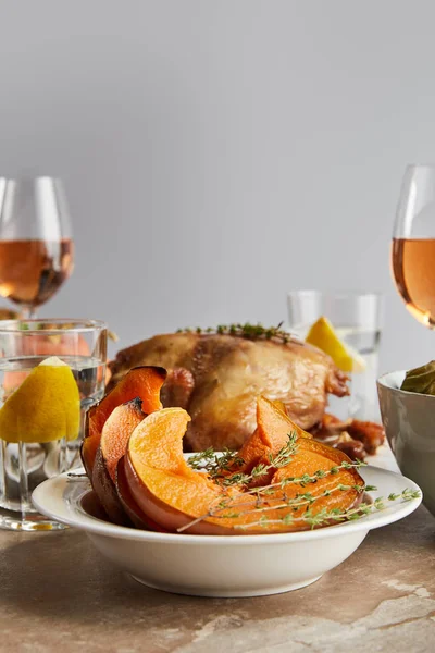 Selective focus of sliced baked pumpkin near grilled turkey and glasses with rose wine isolated on grey — Stock Photo