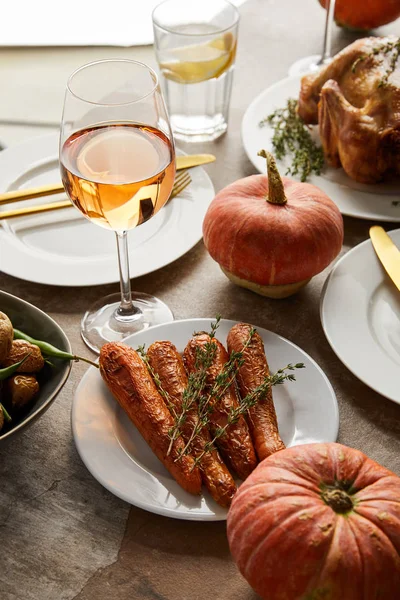 Gegrillte Karotte mit Rosmarin in der Nähe ganzer Kürbisse und Gläser mit Rosenwein und Limonade auf Steintisch — Stockfoto