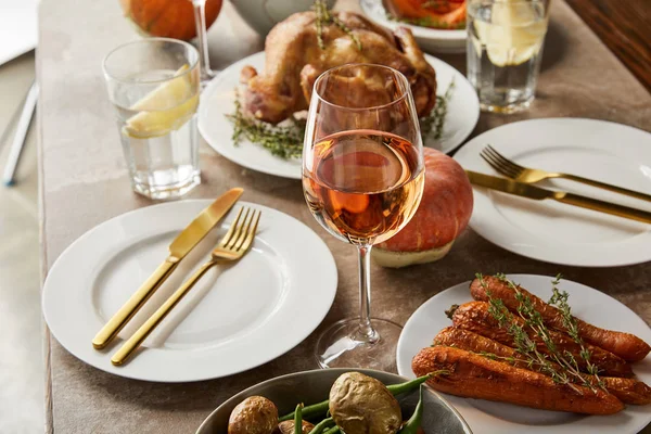 Cena festiva con verdure al forno, tacchino alla griglia e bicchieri con vino rosato sul tavolo di pietra — Foto stock