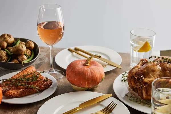 Cena de Acción de Gracias con verduras horneadas, pavo a la parrilla y vasos con vino de rosas y agua de limón aislada en gris - foto de stock