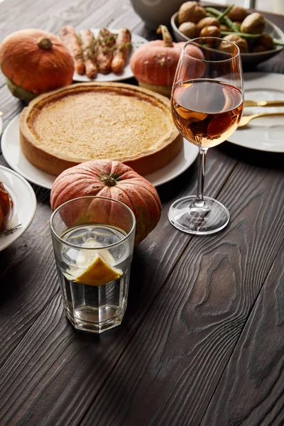 Tarte aux citrouilles, verres au vin rose, légumes cuits au four et citrouilles entières sur table en bois sombre — Photo de stock