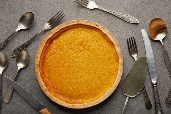 Top view of delicious pumpkin pie near cutlery on grey stone surface — Stock Photo