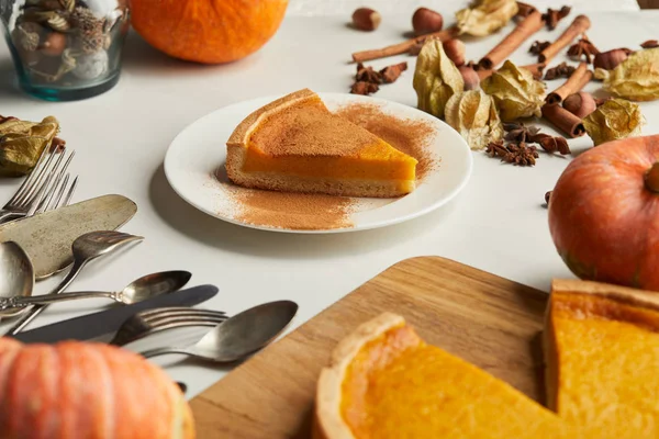 Selective focus of delicious pumpkin pie near cutlery and spices on white marble surface — Stock Photo