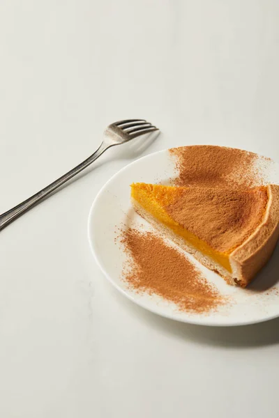 Delicious pumpkin pie with cinnamon powder near fork of white marble table — Stock Photo
