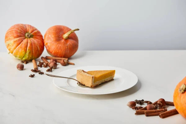 Tasty pumpkin pie near while pumpkins and spices isolated on grey — Stock Photo