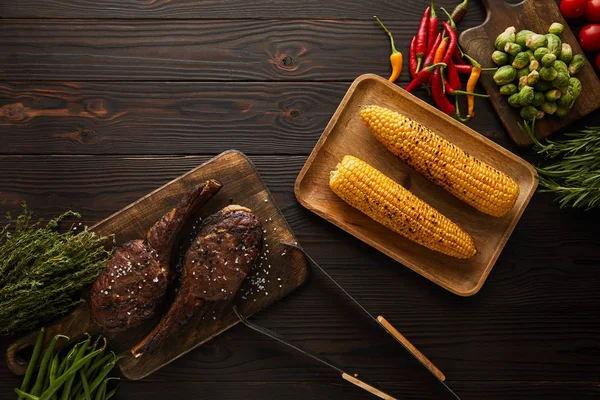 Blick von oben auf Fleisch, Mais, Chilischoten, Kirschtomaten, grüne Erbsen, Grün, Rosenkohl und Pinzette — Stockfoto