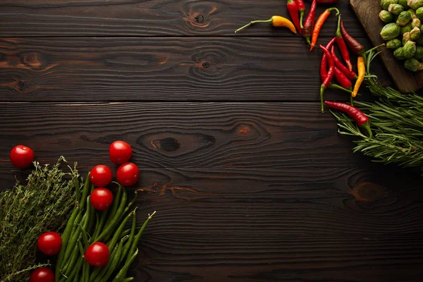 Top view of chili peppers, cherry tomatoes, green peas, greenery, brussels sprouts on cutting board — Stock Photo