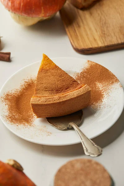 Foco seletivo de deliciosa torta de abóbora com canela em pó na placa com espátula na mesa de mármore branco — Fotografia de Stock