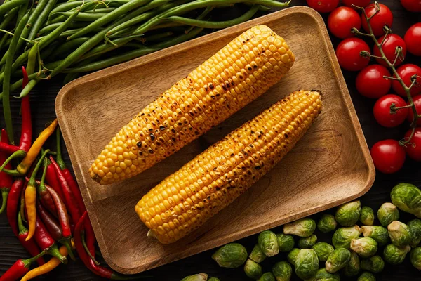 Top view of corn, chili peppers, cherry tomatoes, green peas, brussels sprouts — Stock Photo