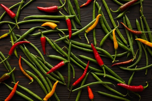 Top view of chili peppers and green peas on wooden table — Stock Photo