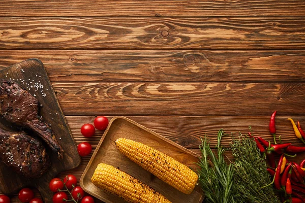 Top view of meat, corn, chili peppers, cherry tomatoes, asparagus, greenery — Stock Photo