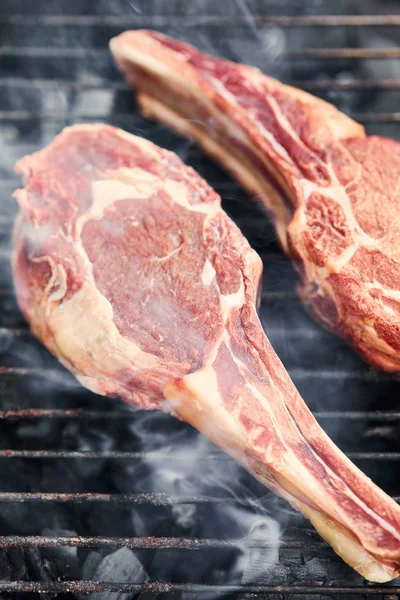 Raw meat grilling on barbecue grid and coal pieces outside — Stock Photo